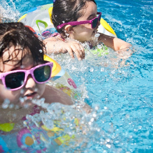 two girls in floaters, play in the pool