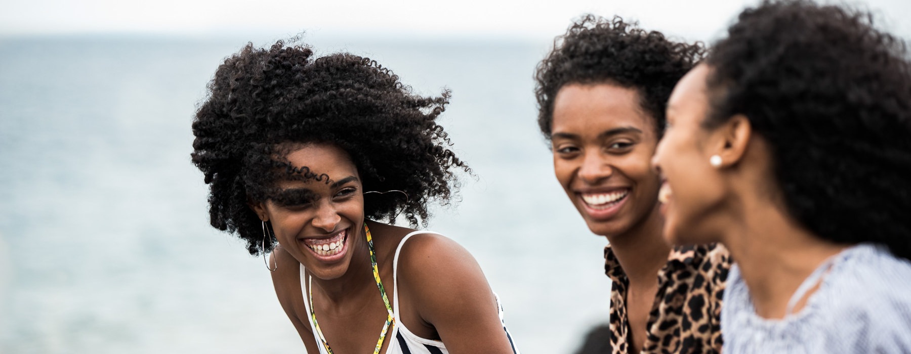 young women laugh together at the beach